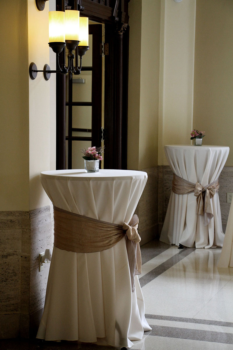 120" Round Ivory Solid Tablecover On A 30" Round Cocktail Table With A 12"x120" Iridescent Crush Camel Tablerunner Tied As A Bow